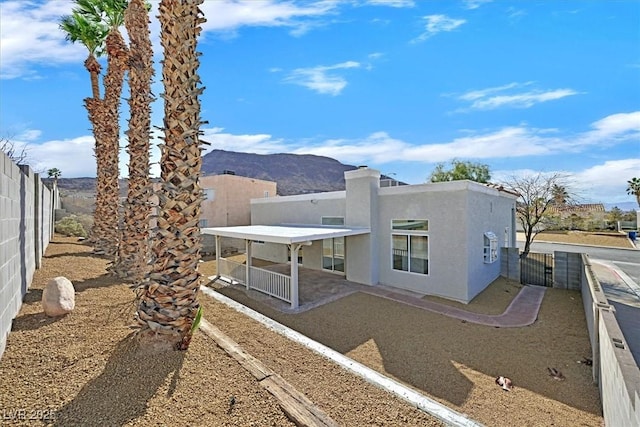 rear view of property with a patio area, a fenced backyard, a mountain view, and stucco siding