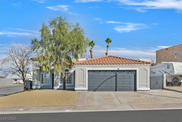 mediterranean / spanish house featuring an attached garage, stucco siding, concrete driveway, and a tiled roof