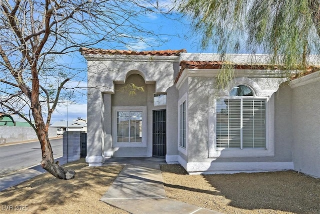 doorway to property with a tile roof and stucco siding