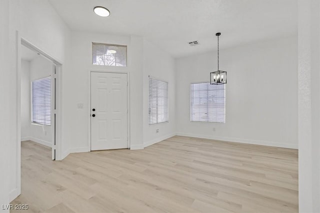 entrance foyer featuring a chandelier, a wealth of natural light, light wood-style flooring, and baseboards