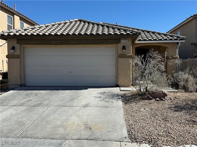 view of front of home featuring driveway, a tiled roof, an attached garage, and stucco siding