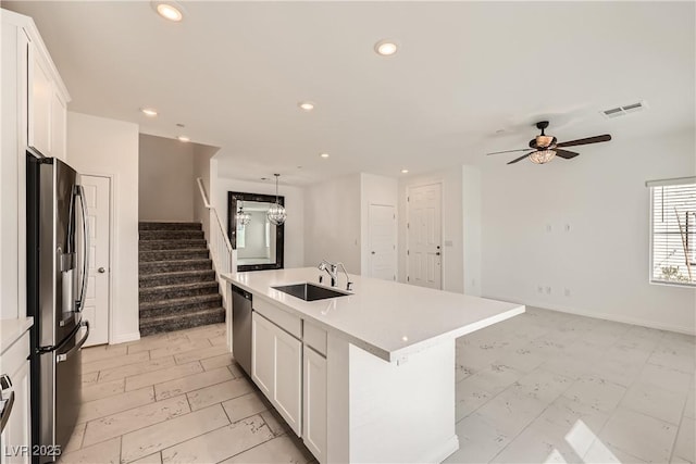 kitchen featuring recessed lighting, appliances with stainless steel finishes, white cabinets, a sink, and an island with sink