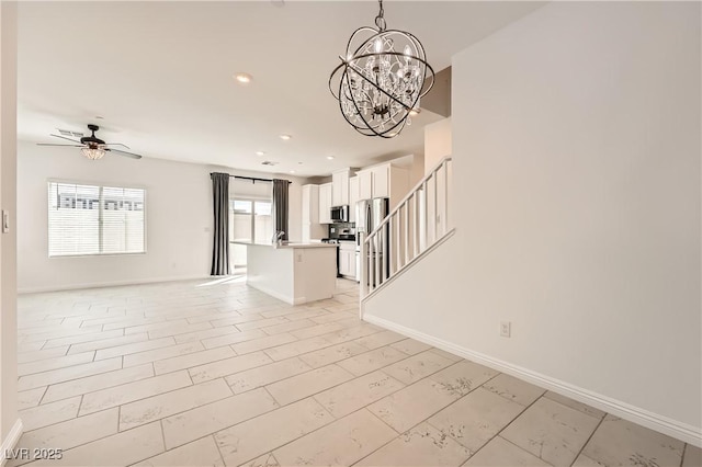 interior space featuring stairs, recessed lighting, baseboards, and ceiling fan with notable chandelier