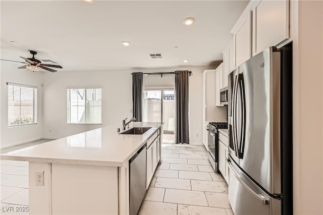 kitchen featuring a sink, visible vents, appliances with stainless steel finishes, plenty of natural light, and a center island with sink