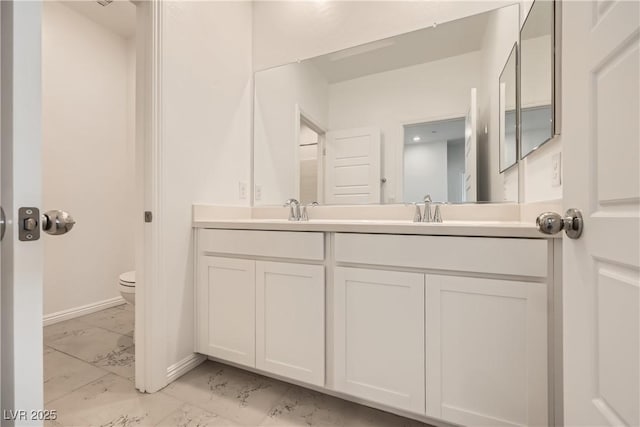 bathroom featuring marble finish floor, a sink, toilet, and double vanity