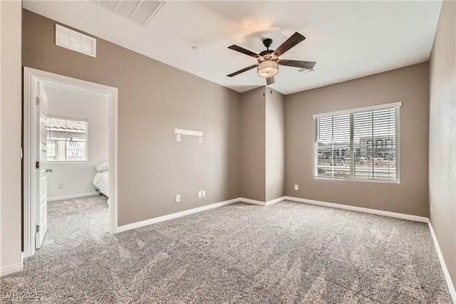 carpeted spare room with a ceiling fan, visible vents, and baseboards