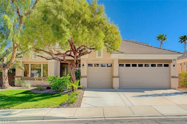 view of front of home featuring a tiled roof, an attached garage, driveway, and stucco siding