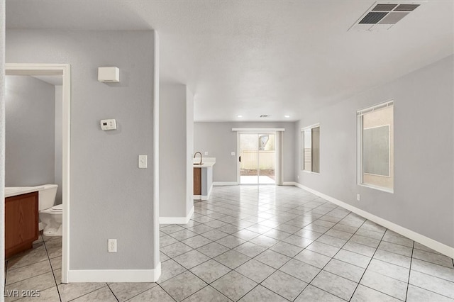 unfurnished room featuring light tile patterned flooring, a sink, visible vents, and baseboards