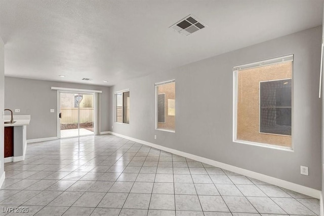 empty room with light tile patterned flooring, visible vents, and baseboards