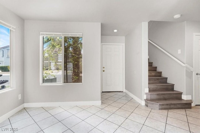 foyer entrance with a wealth of natural light, light tile patterned flooring, and baseboards