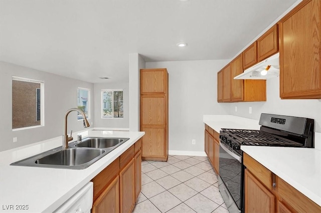 kitchen with light tile patterned flooring, under cabinet range hood, a sink, light countertops, and gas range