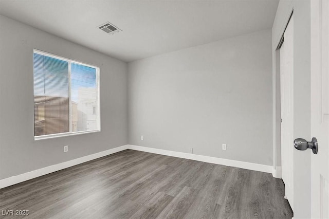 unfurnished bedroom featuring a closet, wood finished floors, visible vents, and baseboards