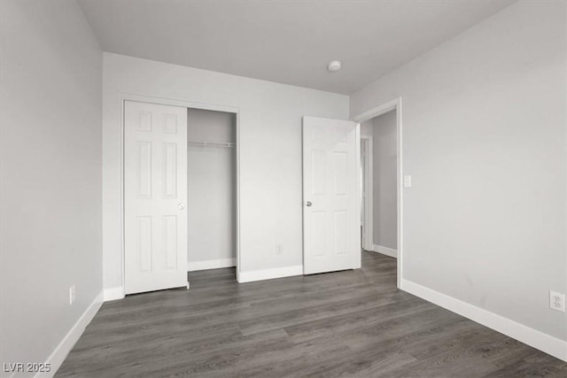 unfurnished bedroom with a closet, dark wood finished floors, and baseboards