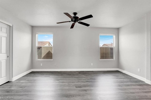 empty room with plenty of natural light, wood finished floors, and baseboards