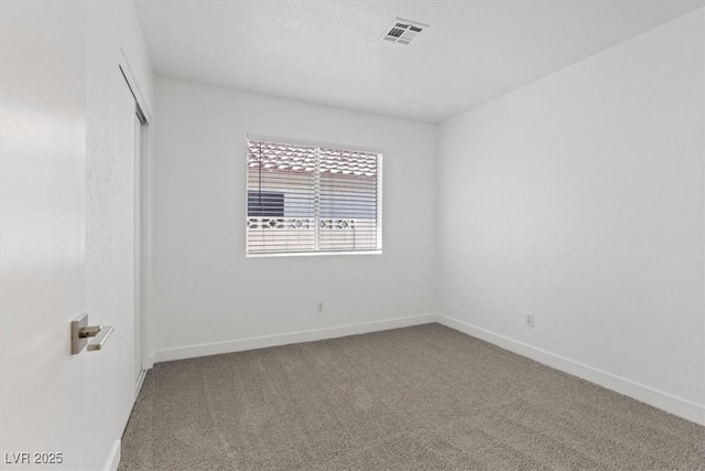 unfurnished room with carpet, visible vents, and baseboards