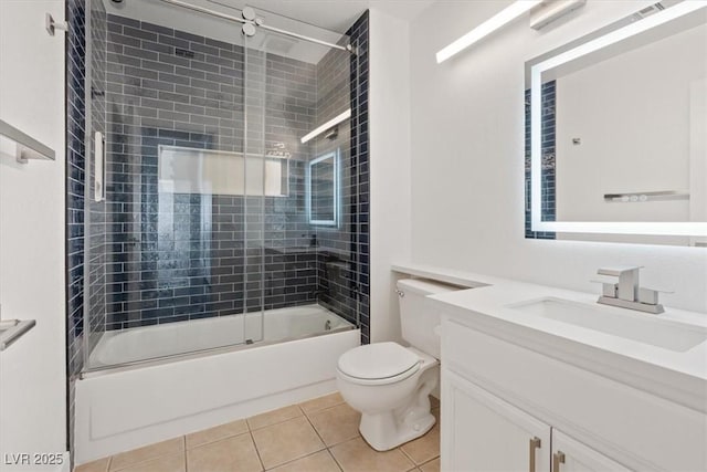 bathroom featuring toilet, tile patterned flooring, combined bath / shower with glass door, and vanity