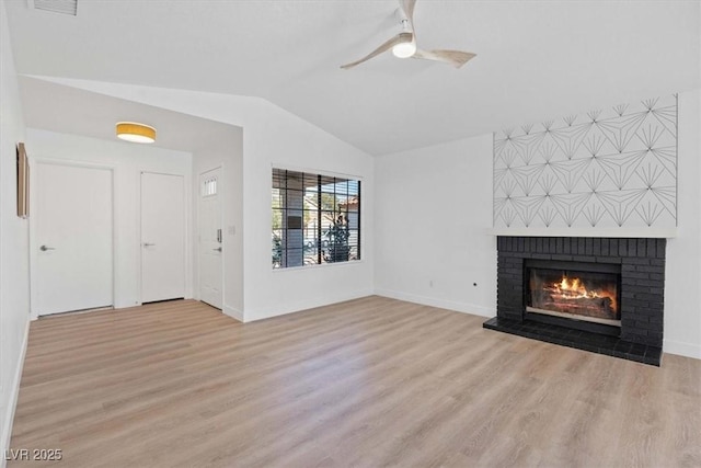 unfurnished living room with a brick fireplace, baseboards, lofted ceiling, ceiling fan, and light wood-style floors