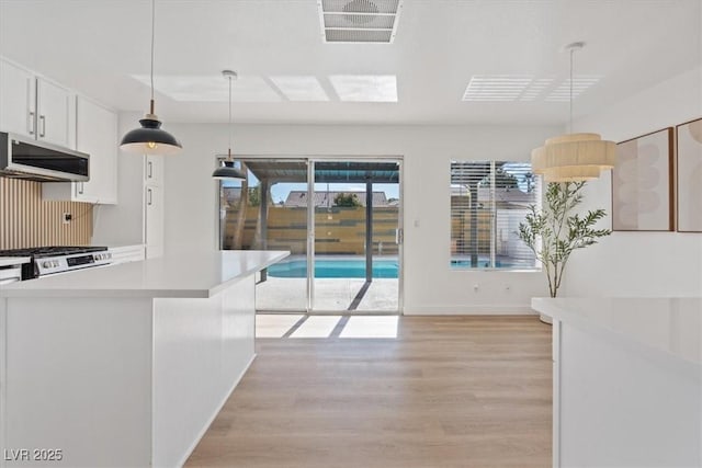 kitchen featuring light wood-style flooring, visible vents, light countertops, range hood, and gas range oven