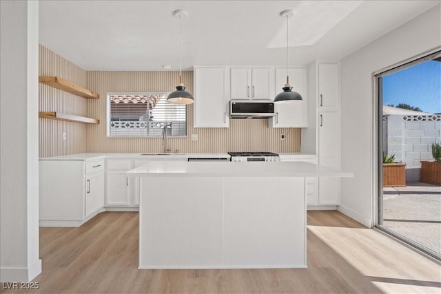 kitchen featuring light wood-style floors, white cabinets, ventilation hood, and a center island