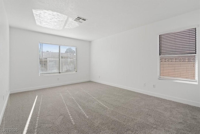 spare room with light colored carpet, visible vents, and baseboards