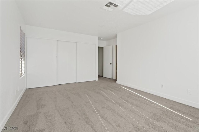 unfurnished bedroom with baseboards, carpet, visible vents, and a closet