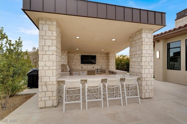 view of patio with area for grilling, exterior kitchen, and outdoor wet bar