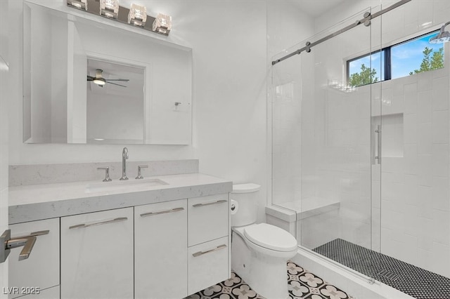 bathroom featuring a stall shower, ceiling fan, vanity, and toilet