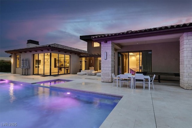 rear view of property featuring a storage structure, an outdoor structure, an outdoor pool, a chimney, and a patio area