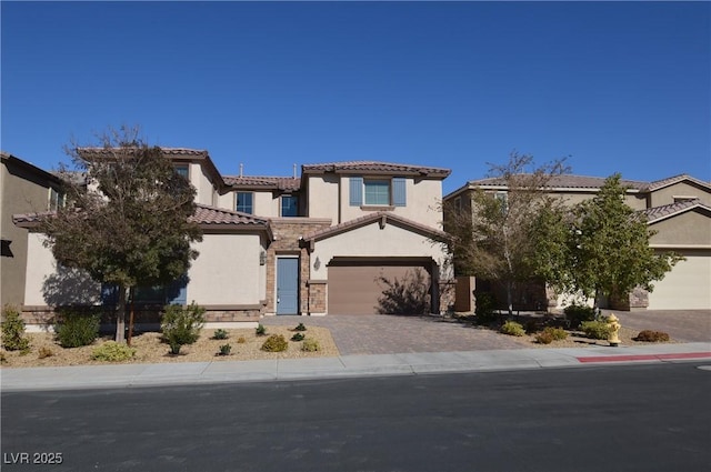 mediterranean / spanish-style house with a garage, stone siding, a tiled roof, decorative driveway, and stucco siding