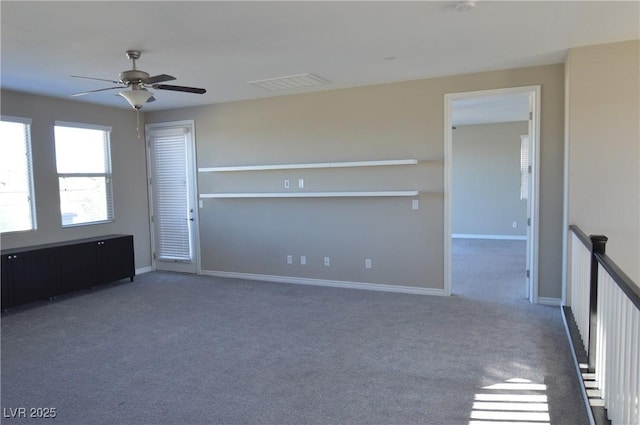 carpeted spare room featuring a ceiling fan, visible vents, and baseboards