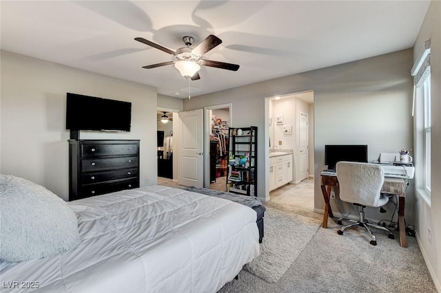 bedroom with a spacious closet, light carpet, a closet, ensuite bath, and a ceiling fan