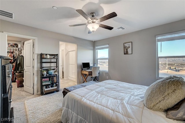 bedroom featuring a walk in closet, visible vents, a closet, and light carpet