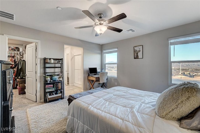 bedroom with a spacious closet, a closet, visible vents, and light colored carpet