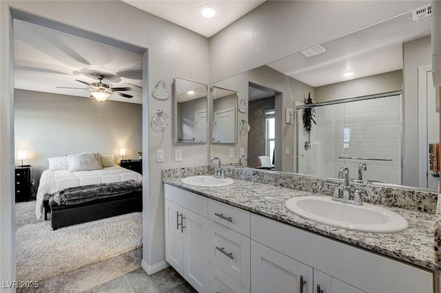 bathroom featuring double vanity, connected bathroom, a shower stall, and a sink