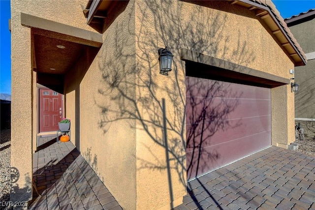 view of side of home featuring stucco siding and a garage