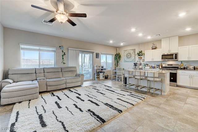 living room with plenty of natural light, a ceiling fan, visible vents, and recessed lighting