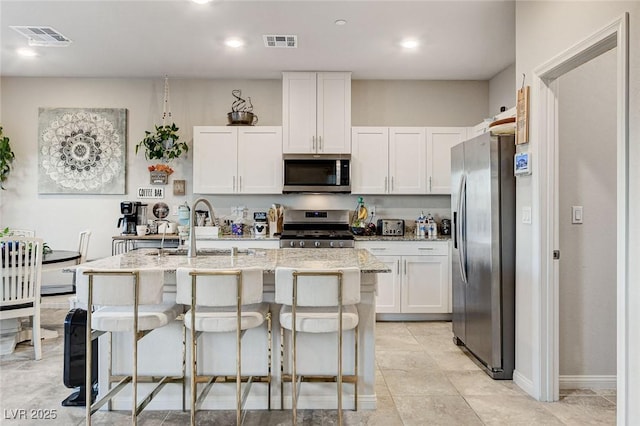 kitchen featuring visible vents, light stone countertops, appliances with stainless steel finishes, and white cabinets