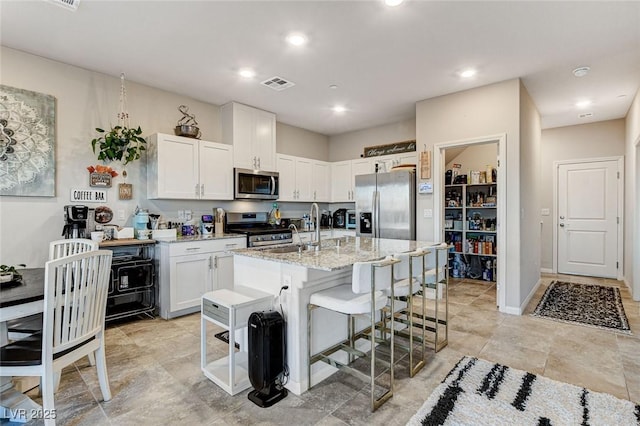 kitchen featuring a sink, stainless steel appliances, visible vents, and white cabinetry