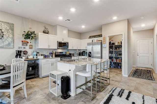 kitchen with white cabinets, appliances with stainless steel finishes, visible vents, and a sink