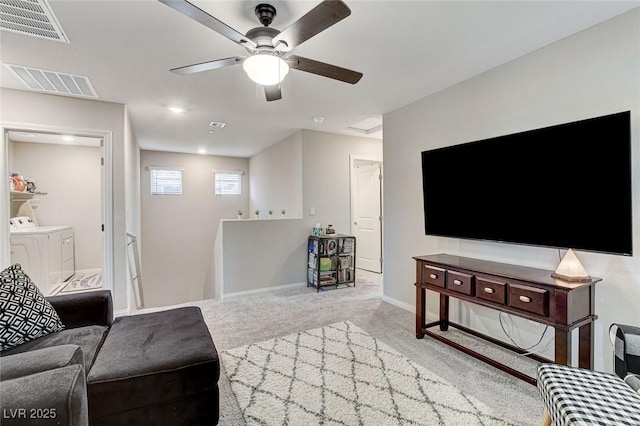 carpeted living room with ceiling fan, baseboards, visible vents, and washing machine and clothes dryer