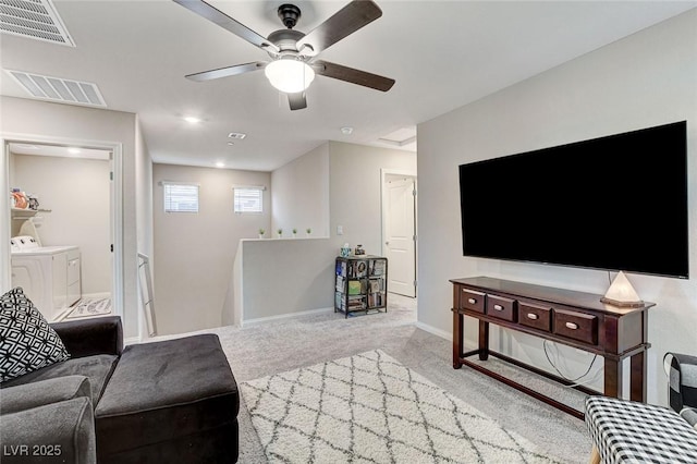 carpeted living area with washing machine and clothes dryer, ceiling fan, baseboards, and visible vents