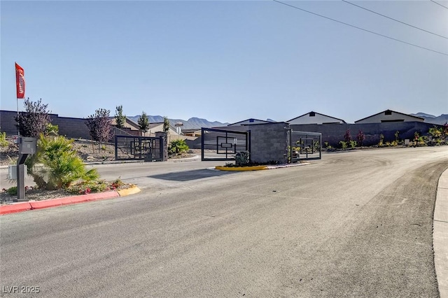 view of road with a gated entry, sidewalks, curbs, and a gate