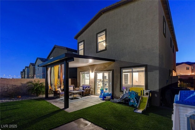 back of house with a yard, stucco siding, a patio, and fence