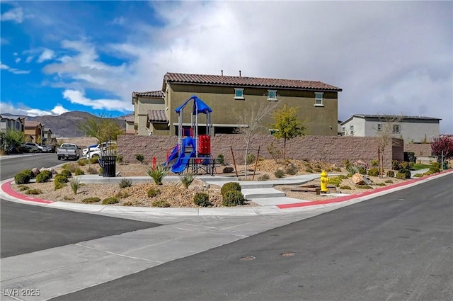 view of front of home with a tile roof, a mountain view, and stucco siding