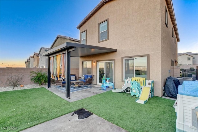 rear view of house featuring stucco siding, a patio, a yard, and a fenced backyard