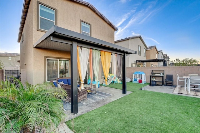 rear view of property with stucco siding, fence, a lawn, and a patio