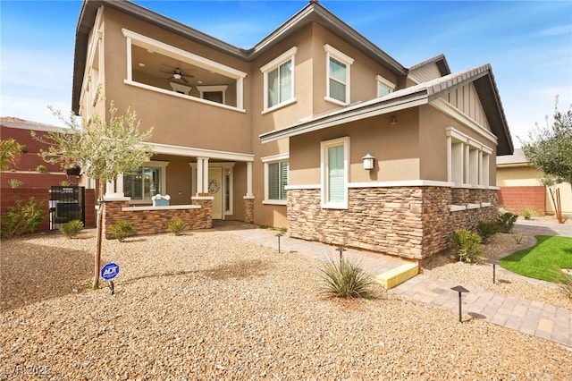 view of front facade featuring a porch, fence, stone siding, and stucco siding