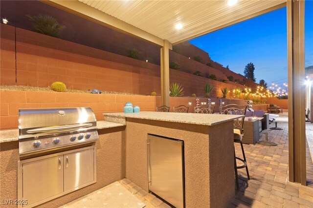 view of patio featuring area for grilling, an outdoor kitchen, fence private yard, and outdoor dry bar