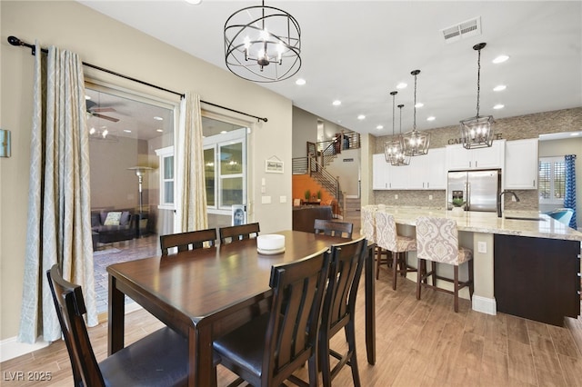 dining space with recessed lighting, light wood-type flooring, visible vents, and ceiling fan with notable chandelier