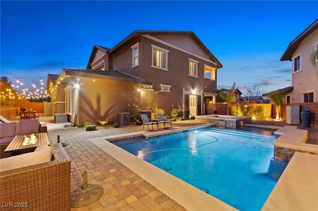 back of property at dusk with central AC, fence, a fenced in pool, an in ground hot tub, and a patio area